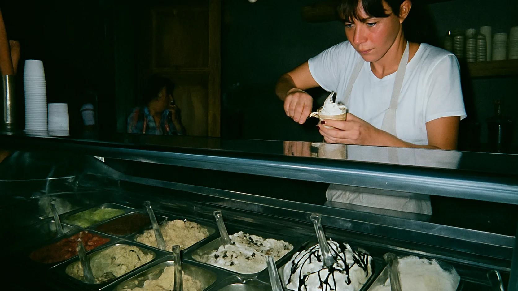 Mitarbeiterin portioniert Eis hinter der Theke einer kleinen Eisdiele