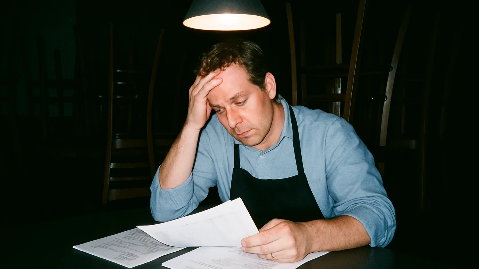 Müder Restaurantleiter prüft abends Papierberichte an der Theke